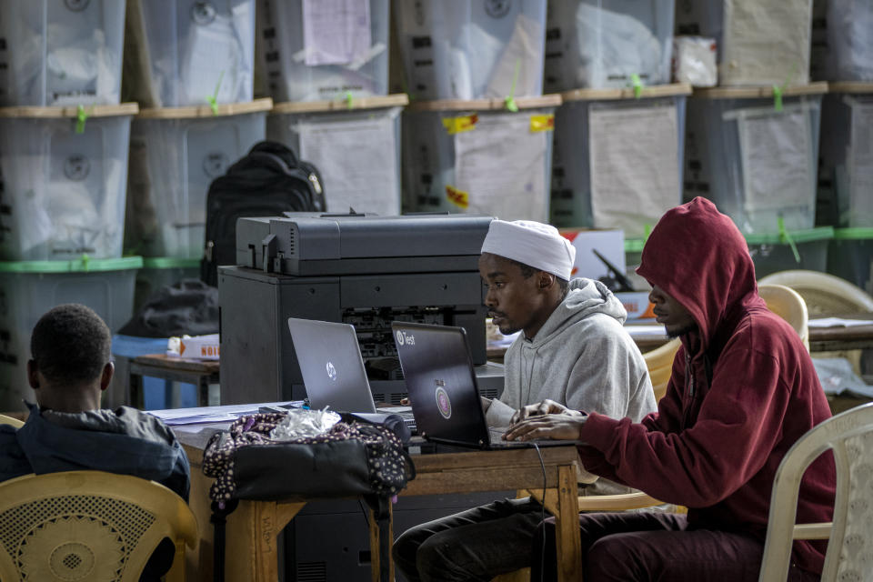 Electoral workers sit next to stacked ballot boxes after tallying finished in the Shauri Moyo area of Nairobi, Kenya Friday, Aug. 12, 2022. Kenyans are waiting for the results of a close presidential election in which the turnout was lower than usual. (AP Photo/Ben Curtis)