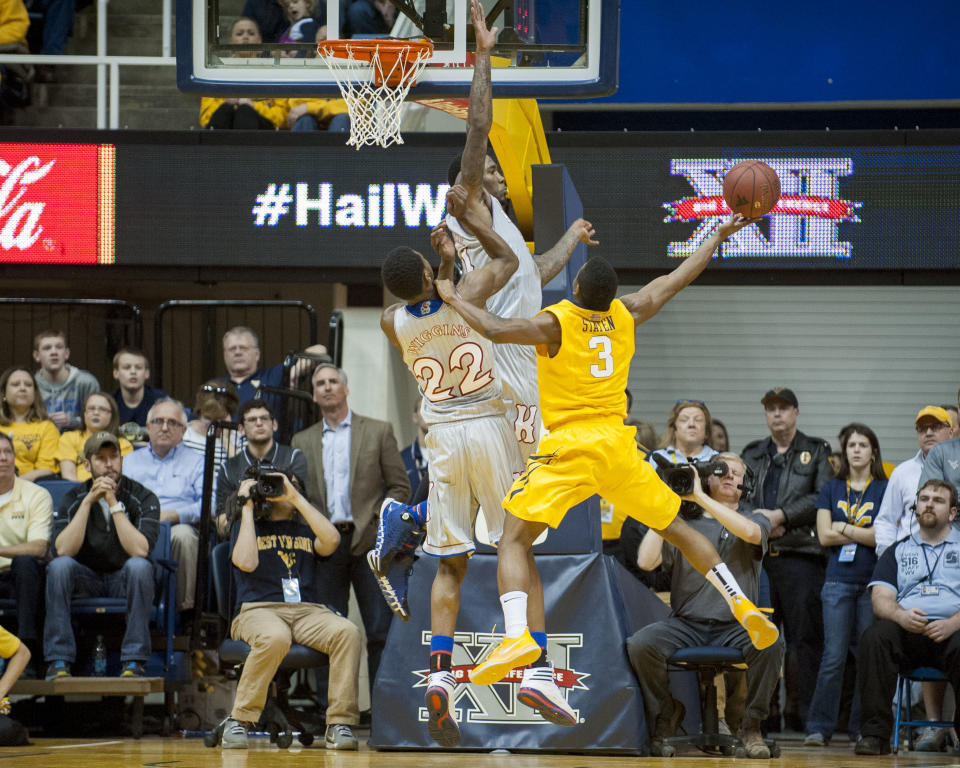 West Virginia's Juwan Staten, right, drives to the basket as Kansas' Andrew Wiggins (22) and Jamari Traylor defends during the first half of an NCAA college basketball game Saturday, March 8, 2014, in Morgantown, W.Va. (AP Photo/Andrew Ferguson)