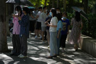 Residents stand underneath tree to avoid the hot sun as they line up for their routine coronavirus tests at a testing site in Beijing, Thursday, July 7, 2022. The Chinese capital has issued a mandate requiring people to show proof of COVID-19 vaccination before they can enter some public spaces including gyms, museums and libraries, drawing concern from city residents over the sudden policy announcement and its impact on their daily lives. (AP Photo/Andy Wong)