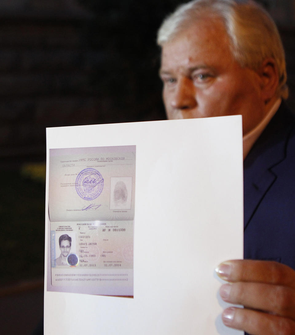 Lawyer Anatoly Kucherena shows a picture of fugitive former U.S. spy agency contractor Edward Snowden in his new refugee documents granted by Russia during a news conference in Moscow August 1, 2013. Snowden slipped quietly out of the airport on Thursday after securing temporary asylum in Russia, ending more than a month in limbo in the transit area.  REUTERS/Maxim Shemetov (RUSSIA - Tags: POLITICS CRIME LAW)