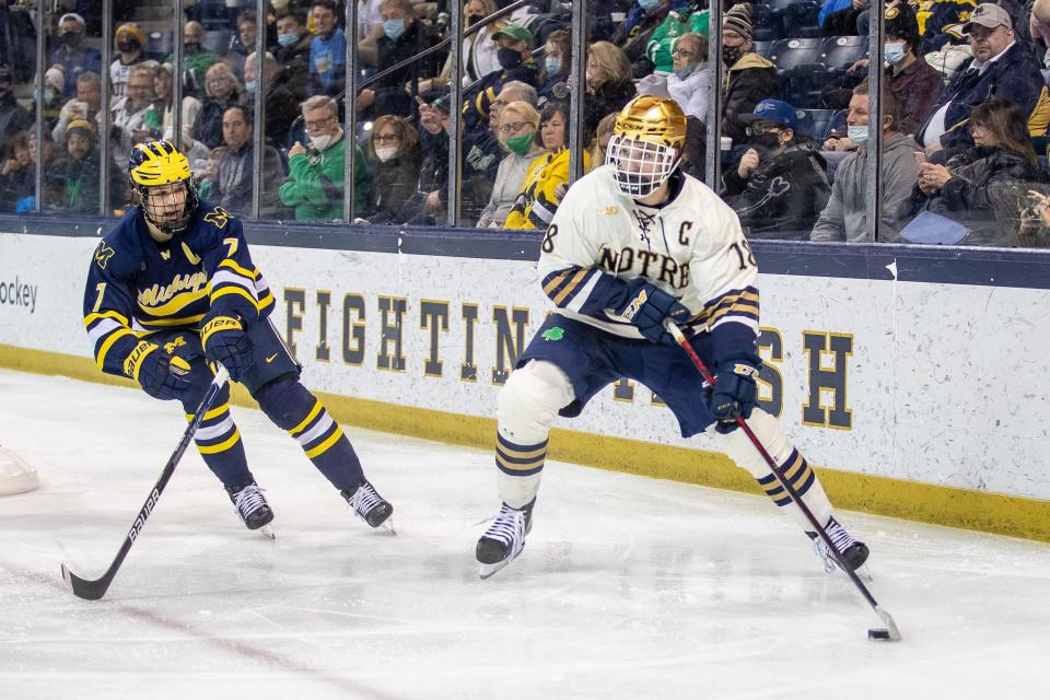 Notre Dame forward Graham Slaggert (18) skates with the puck as Michigan defenseman Nick Blankenburg (7) back checks during the Notre Dame-Michigan Big Ten  hockey game on Friday, February 25, 2022, at Compton Family Ice Arena in South Bend, Indiana.