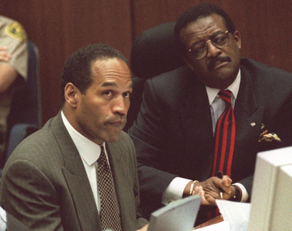 Text: O.J. Simpson looks at an overhead screen as biochemist Robin Cotton explains genetic markers on DNA film during the Simpson double-murder trial in Los Angeles Wednesday morning, May 10, 1995. Cotton for the first time linked Simpson to the murders of his ex-wife and her friend, telling jurors DNA in a blood drop found near the bodies matched Simpson's. At right is Simpson's attorney, Johnnie Cochran Jr.(AP Photo/Vince Bucci, Pool)