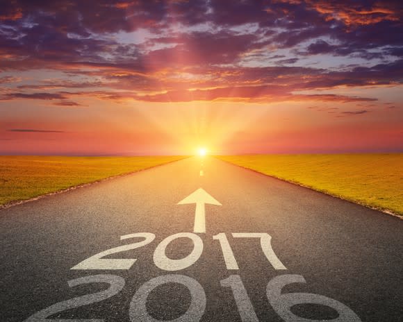 2016 and 2017 written on a road, with arrow pointing toward sun on the horizon.