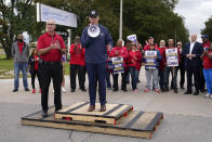 File - United Auto Workers President Shawn Fain, left, listens as President Joe Biden speaks to striking UAW members outside a General Motors facility on Sept. 26, 2023, in Van Buren Township, Mich. Throughout its 5-week-old strikes against Detroit’s automakers, the United Auto Workers union has cast an emphatically combative stance, reflecting the style of Fain, its pugnacious leader. (AP Photo/Evan Vucci, File)