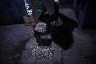 Un empleado del crematorio recoge las cenizas que ha sacado del horno antes de meterlas en una urna que entregará a sus familiares. (Photo by PEDRO PARDO/AFP via Getty Images)