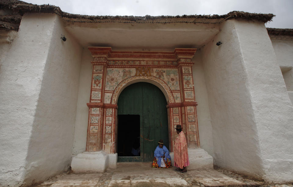 Two Aymara women stand at the door of the Sistine Chapel of Los Andes in Curahuara de Carangas, Oruro department, 260 km. (160 miles) south from La Paz, Bolivia, Saturday, Dec. 8, 2012. Built in 1608 to evangelize indigenous Bolivians into the Roman Catholic faith, the chapel these days attracts both the faithful and tourists. (AP Photo/Juan Karita)