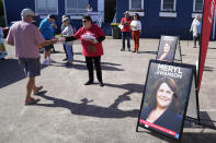 A volunteer hands out "how to vote" cards to voters outside polling booth in Nelson Bay, Australia, Monday, May 9, 2022. Early voting has begun in Australia's federal election with the opposition party hoping the first ballots will reflect its lead over the government in an opinion poll. (AP Photo/Mark Baker)