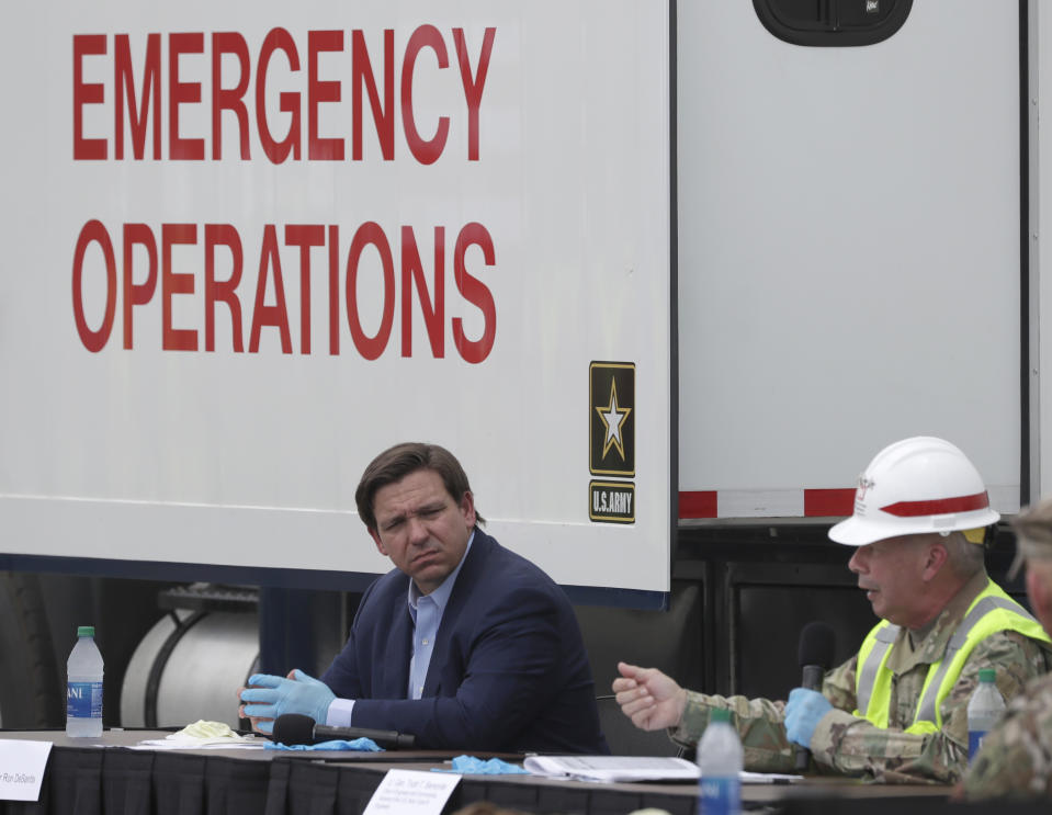 Florida Gov. Ron DeSantis, center, listens as Chief of Engineers and Commanding General of the U.S. Army Corps of Engineers Lt. Gen. Todd T. Semonite, right, speaks during a news conference in front of a U.S. Army Corps of Engineers mobile command center at the Miami Beach Convention Center, Wednesday, April 8, 2020, in Miami Beach, Fla. The Corps of Engineers will transform the newly renovated facility into a hospital by April 27, news outlets reported Tuesday. (AP Photo/Wilfredo Lee)