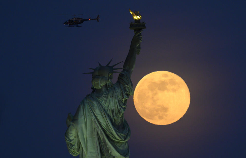 À New York, la statue de la Liberté a fait face à une splendide lune rousse. (Photo by Johannes EISELE / AFP)