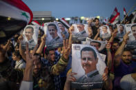 Syrian President Bashar Assad supporters hold up national flags and pictures of Assad as they celebrate at Omayyad Square, in Damascus, Syria, Thursday, May 27, 2021. (AP Photo/Hassan Ammar)