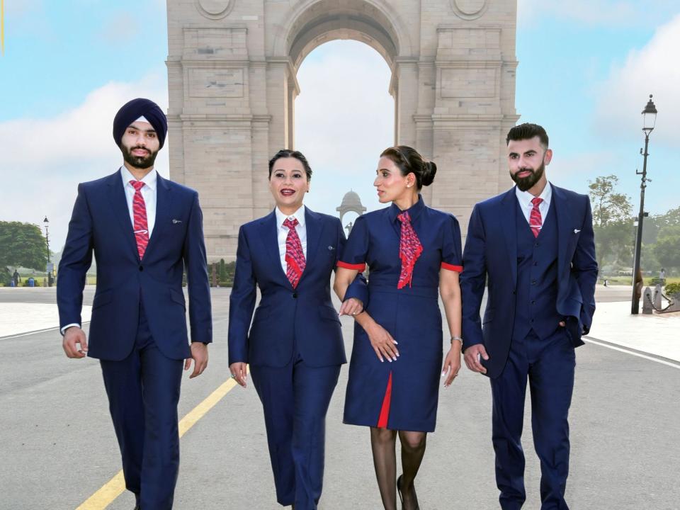 BA flight attendants in uniform walking in front of a big arch in India.