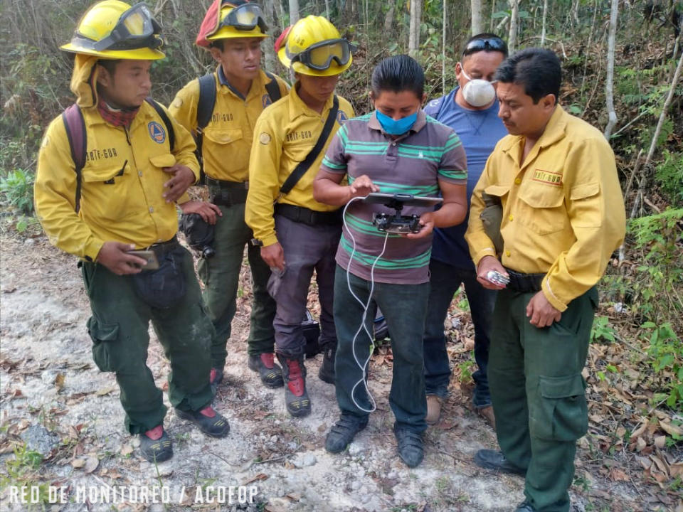 In this undated photo provided by the Association of Forest Communities of Petén on June 2020, Alvaro Ba operates a drone within the BioItza reserve in northern Guatemala to assess the characteristics of a forest fire. Alvaro is an associate of one of the community organizations that forms ACOFOP, which works to protect forests within Guatemala's Maya Biosphere. In 2020, the region has experienced a worrisome uptick in fires set illegally to clear land, while government resources to control flames have been diverted to manage the COVID-19 pandemic. (Aderito Chayax/ACOFOP via AP)