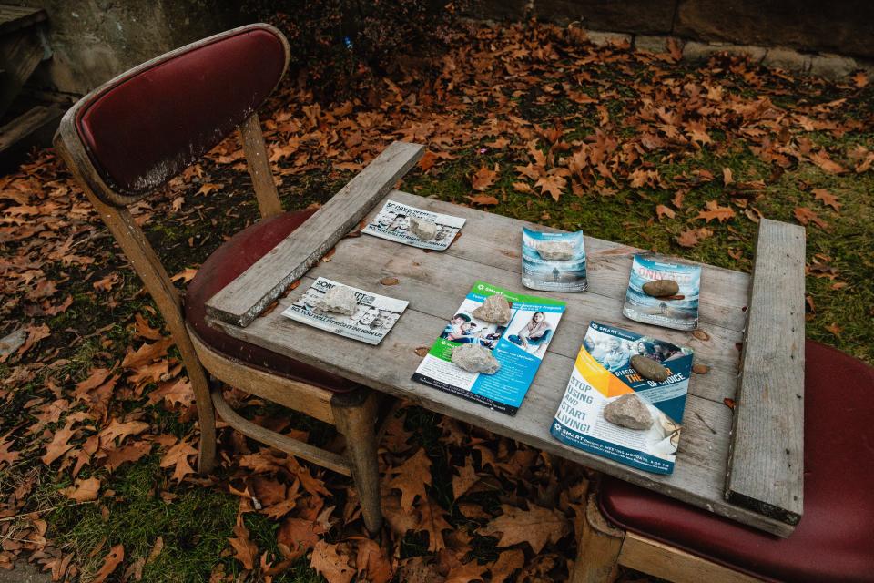 Flyers for people in need of addiction support are displayed on an improvised table on Monday in an area of New Philadelphia where multiple vacant homes have been taken over and condemned by the city.