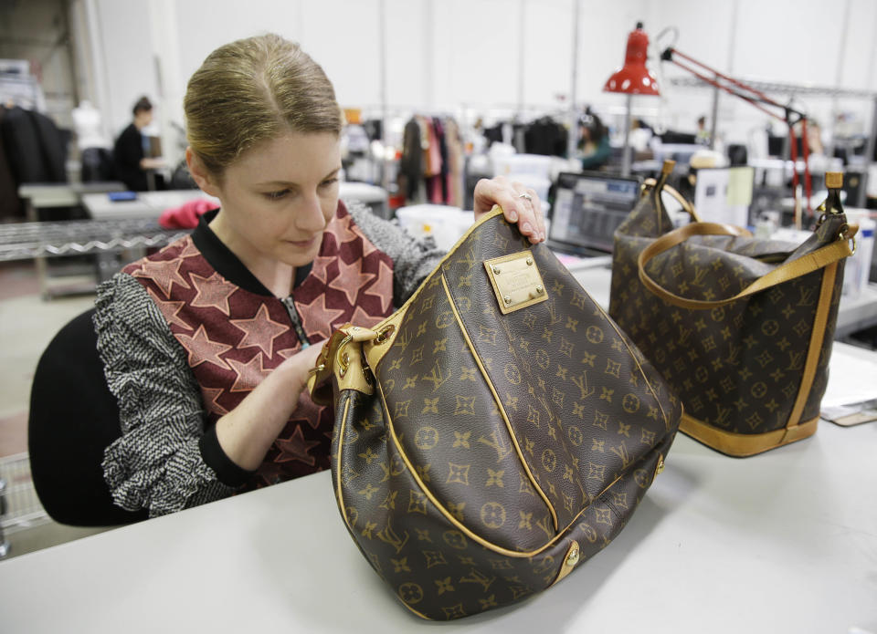 In this photo taken Wednesday, April 9, 2014, Jenna Starr inspects a pair of Louis Vuitton handbags to authenticate them and make sure they meet brand standards at the headquarters of The RealReal in San Francisco. An explosion of resale online sites from RealReal to Chairish that allows shoppers to easily trade in their gently used top brand handbags, furniture and gadgets for cash is changing the way Americans buy. The ease of reselling their possessions allows consumers to keep refreshing their wardrobes and homes without feeling guilty. (AP Photo/Eric Risberg)