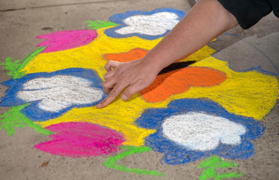 Arts activist Joy Neas creates a colorful chalk drawing out side of Limitless Axes and Ales at Lincoln Center in Stockton. Neas was part of a small group making chalk drawings on the shopping center's sidewalks for this weekend's appearance of the Easter Bunny.