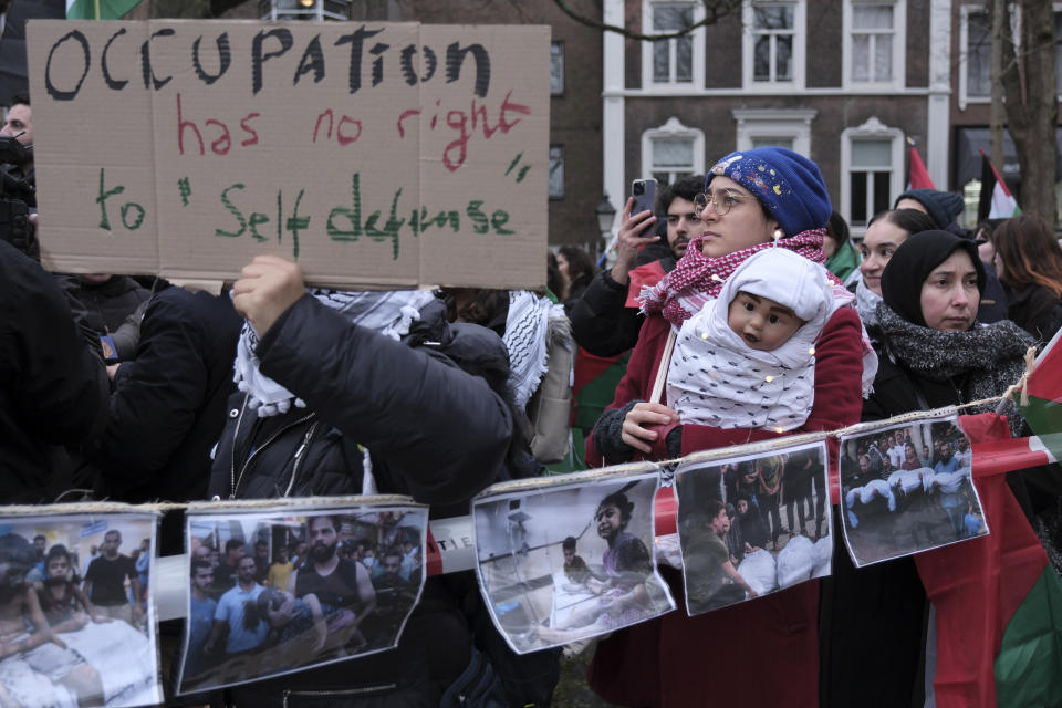 FILE - Protesters carry flags and banners outside the International Court of Justice in The Hague, Netherlands, Friday, Jan. 12, 2024. The United Nations' top court opened hearings Thursday into South Africa's allegation that Israel's war with Hamas amounts to genocide against Palestinians, a claim that Israel strongly denies. (AP Photo/Patrick Post, File)