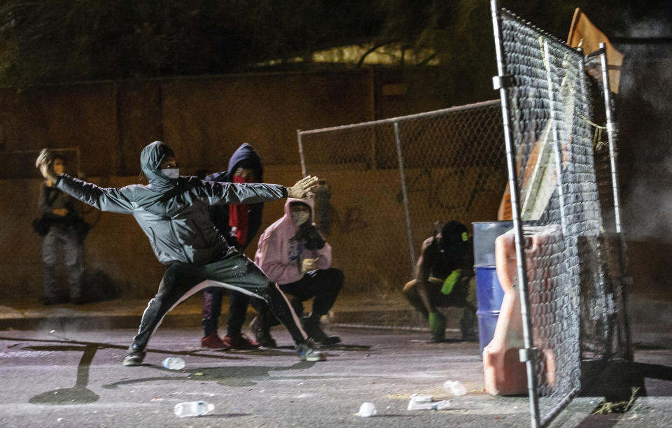 A man throws an object towards the Tucson Police Department during an early morning protest over the death of George Floyd, Sunday, May 31, 2020, in Tucson, Ariz. Protests were held throughout the country over the death of Floyd, a black man who died after being restrained by Minneapolis police officers on May 25. (Josh Galemore/Arizona Daily Star via AP)