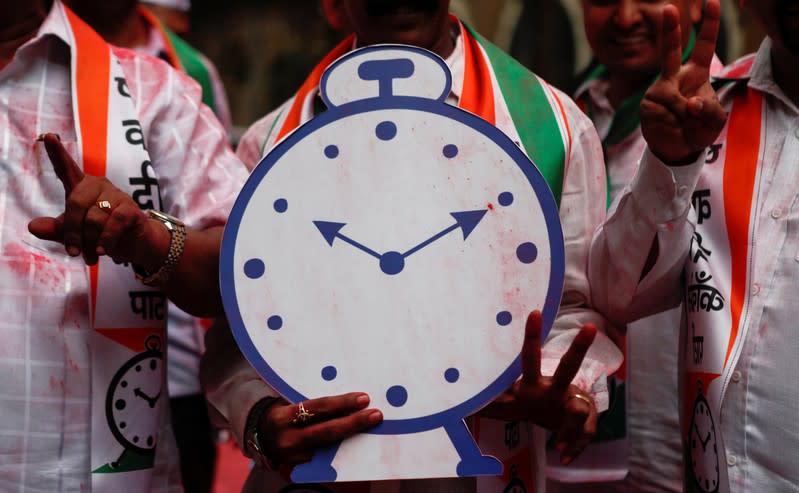 A supporter of the Nationalist Congress Party (NCP) holds a cut-out of the party symbol outside the party office after learning of initial poll results in Mumbai