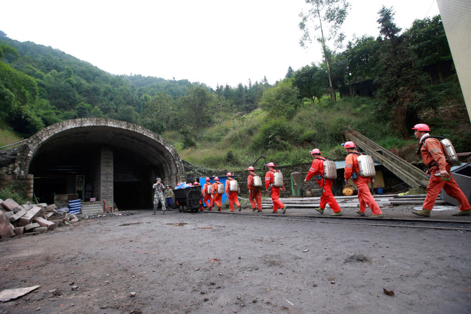 Rescuers carry materials and walk to a cave at the site of a coal mine explosion in Chongqing
