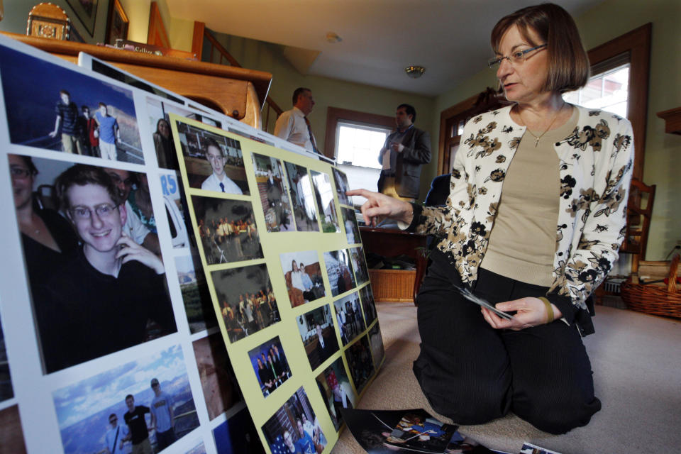 FILE - In this Dec. 9, 2011, file photo, Jane Clementi, right, the mother of Tyler Clementi, looks at family photographs of her son as her husband Joseph Clementi, back left, the father of Tyler Clementi, speaks to a reporter in their home in Ridgewood, N.J. Declaring “God is on your side,” a Roman Catholic cardinal, an archbishop and six other U.S. bishops issued a statement Monday, Jan. 25, 2021, expressing support for LGBT youth and denouncing the bullying often directed at them. It was released by the Tyler Clementi Foundation, named for the Rutgers University student who took his own life in 2010 after being targeted by online harassment. (AP Photo/Mel Evans, File)