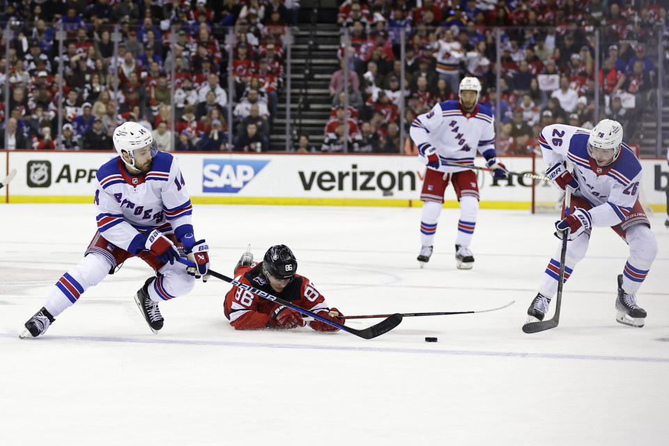 New Jersey Devils center Nico Hischier reaches for the puck between New York Rangers center Tyler Motte (14) and left wing Jimmy Vesey during the first period of Game 7 of an NHL hockey Stanley Cup first-round playoff series Monday, May 1, 2023, in Newark, N.J. (AP Photo/Adam Hunger)