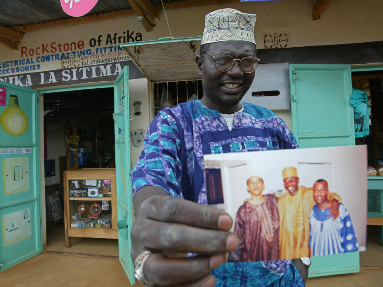 Malik Obama, the older brother of Barack, holds an undated picture outside his shop in Siaya in eastern Kenya: AP