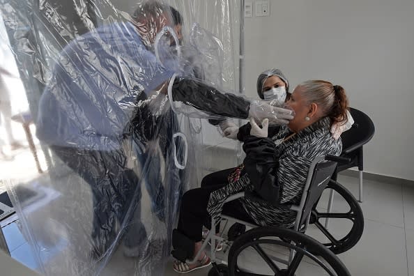 Ossimar Silva (L) touches his 85-year-old mother Carmelita Valverde's face, through a transparent plastic curtain at a senior nursing home in Sao Paulo, Brazil.