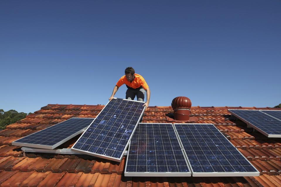 Solar system installer Thomas Bywater adjusts new solar panels on the roof of a house in Sydney in this August 19, 2009 file photo. To match Insight SOLAR/BATTLELINES REUTERS/Tim Wimborne/Files (AUSTRALIA - Tags: ENVIRONMENT ENERGY BUSINESS)