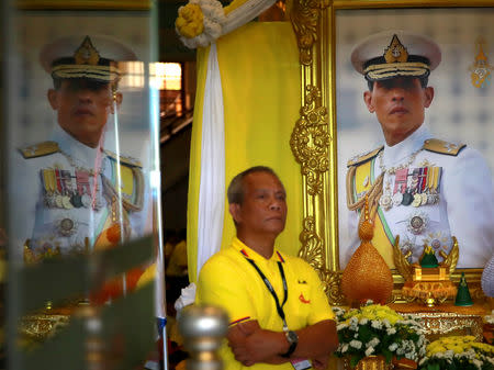 A man stands next to a portrait of Thailand's newly crowned King Maha Vajiralongkorn while waiting for a coronation procession in Bangkok, Thailand May 5, 2019. REUTERS/Navesh Chitrakar