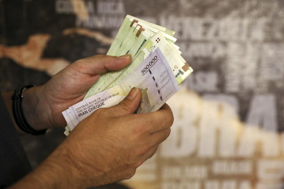 FILE - In this Aug. 21, 2019 file photo, a man counts his banknotes and traveler checks in Tehran, Iran. On Sunday, Sept 20, 2020, Iran dismissed U.S. efforts to restore all U.N. sanctions on the country as mounting economic pressure from Washington pushed the local currency down to its lowest level ever. (AP Photo/Ebrahim Noroozi, File)