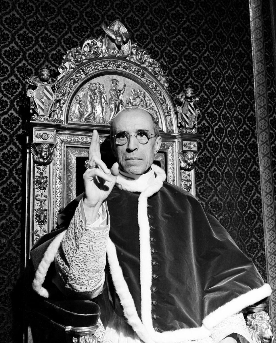 FILE - Pope Pius XII, wearing the ring of St. Peter, raises his right hand in a papal blessing at the Vatican, in Sept. 1945. The Vatican has long defended its World War II-era pope, Pius XII, against criticism that he remained silent as the Holocaust unfolded, insisting that he worked quietly behind the scenes to save lives. Pulitzer Prize-winning author David Kertzer’s “The Pope at War,” which comes out Tuesday, June 7, 2022 in the United States, citing recently opened Vatican archives, suggests the lives the Vatican worked hardest to save were Jews who had converted to Catholicism or were children of Catholic-Jewish “mixed marriages.” (AP Photo, File)