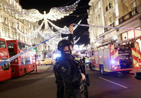 An armed police officer ducks under police tape on Oxford Street, London, Britain November 24, 2017. REUTERS/Simon Dawson