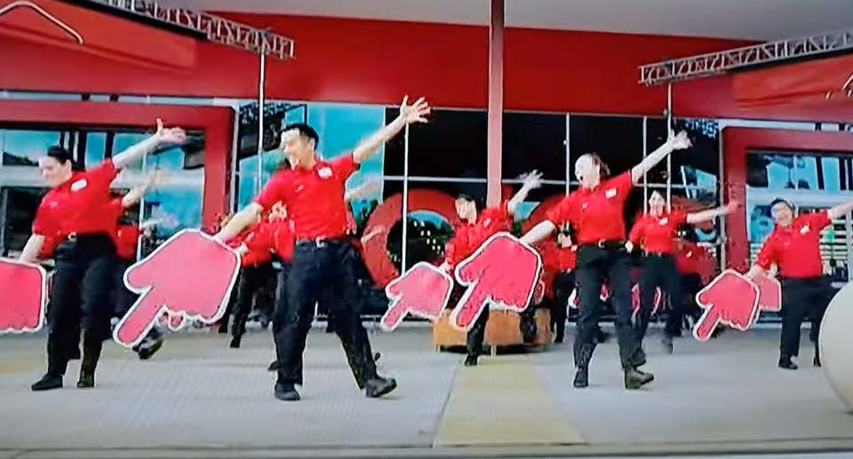 A Coles ad is seen with staff wearing large red hands. 