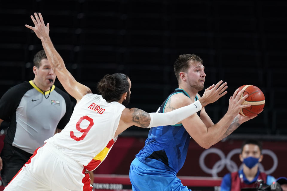Slovenia's Luka Doncic passes ahead of Spain's Ricky Rubio (9) during a men's basketball preliminary round game at the 2020 Summer Olympics, Sunday, Aug. 1, 2021, in Saitama, Japan. (AP Photo/Charlie Neibergall)