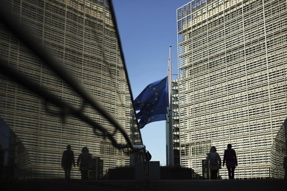 Passers-by walk next to the European Commission headquarters in Brussels, Friday, Feb. 15, 2019. British Prime Minister Theresa May suffered an embarrassing defeat by lawmakers Thursday in a vote that left her bid to secure a European Union divorce deal stuck between an intransigent EU and a resistant U.K. Parliament, with Brexit just six weeks away. (AP Photo/Francisco Seco)