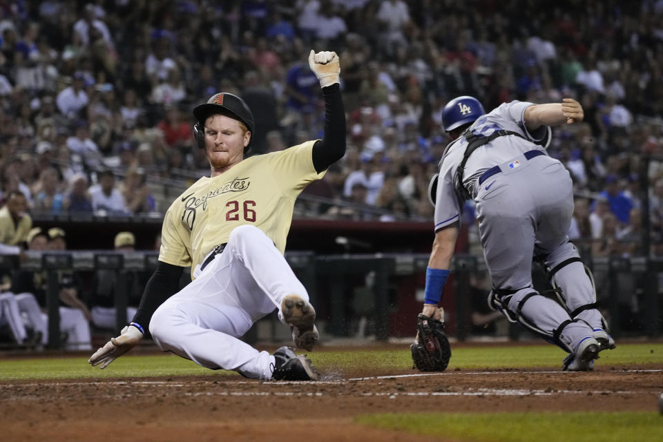 Arizona Diamondbacks' Pavin Smith (26) scores a run behind Los Angeles Dodgers catcher Will Smith on a ball hit by Josh VanMeter in the fifth inning during a baseball game, Friday, Sept. 24, 2021, in Phoenix. (AP Photo/Rick Scuteri)