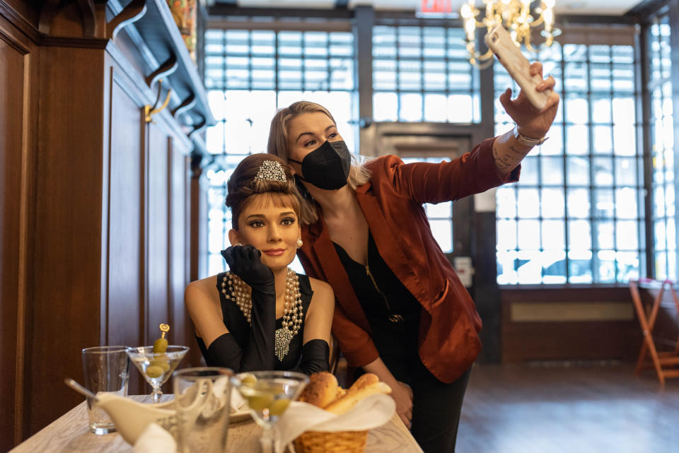 A patron snapping a photo with a wax figure of Audrey Hepborn at Peter Luger's Steakhouse in Brooklyn in March 2021. (Photo: Courtesy of Madame Tussauds)