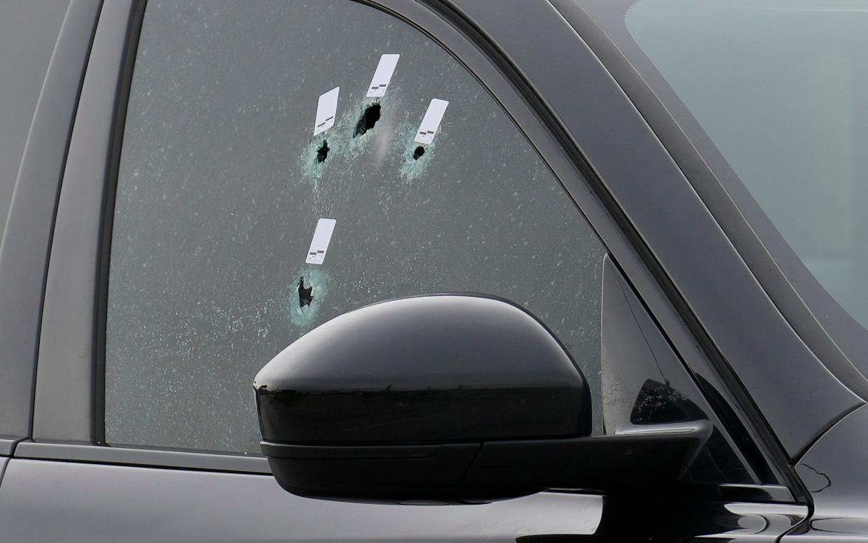 Bullet holes in a passenger-side window of an SUV at the scene