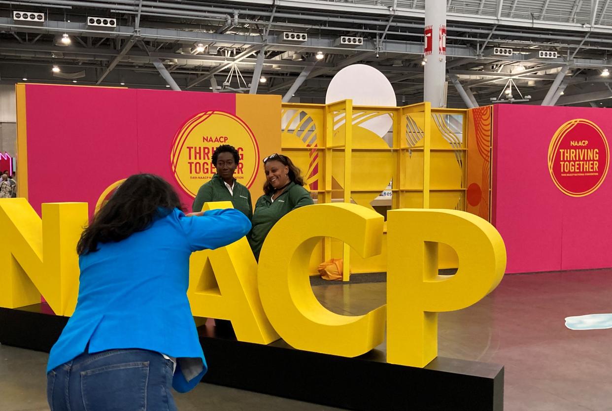 Attendees at the NAACP convention in Boston take photos Friday at The Hub.