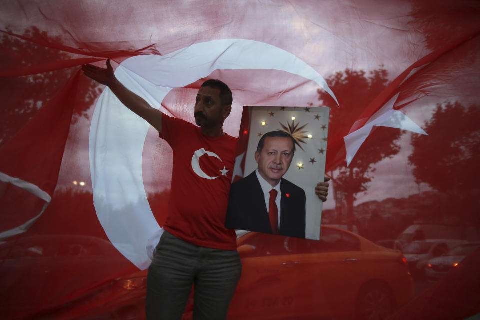 FILE - A man holds a picture of Turkey's President and ruling Justice and Development Party, or AKP, leader Recep Tayyip Erdogan while celebrating outside the party headquarters in Istanbul, on June 24, 2018. (AP Photo/Emrah Gurel)