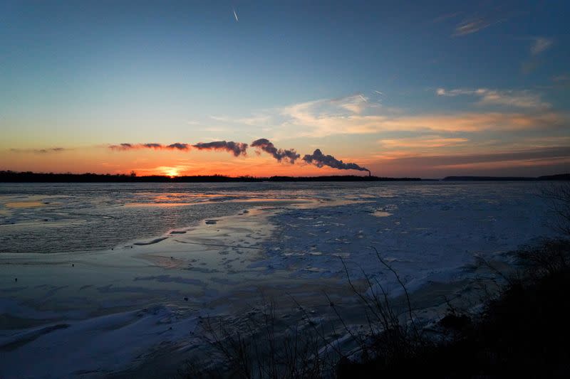 The sun sets on a frozen Mississippi River during cold weather in Alton