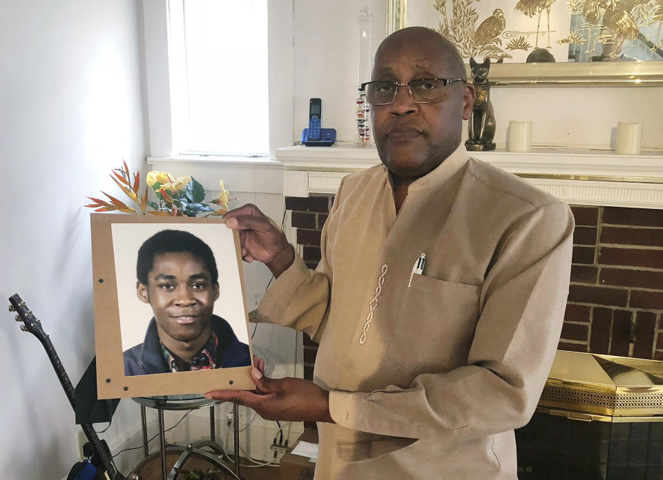 FILE - In this Sept. 5, 2018 file photo, Dia Khafra, father of Askia Khafra, holds a photo of his son in his Silver Springs, Md., home. A jury convicted a wealthy stock trader of second-degree murder and involuntary manslaughter Wednesday, April 24, 2019, in the fiery death of Askia Khafra, who was helping him secretly dig tunnels for an underground nuclear bunker beneath his Maryland home. (AP Photo/Michael Kunzelman, File)
