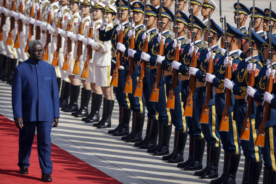 FILE - Solomon Islands Prime Minister Manasseh Sogavare reviews a Chinese honor guard during a welcome ceremony at the Great Hall of the People in Beijing, Wednesday, Oct. 9, 2019. Solomon Islands Prime Minister Sogavare has blamed foreign interference over his government's decision to switch alliances from Taiwan to Beijing for anti-government protests, arson and looting that have ravaged the capital in recent days. (AP Photo/Mark Schiefelbein, File)