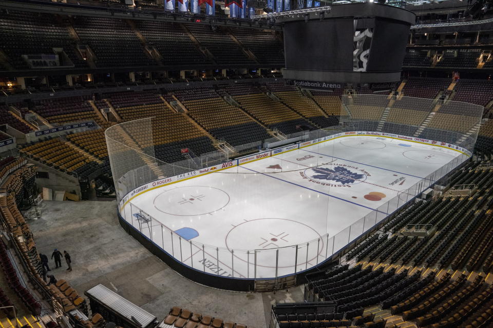 FILE - In this March 12, 2020, file photo, workers stand by after pausing the assembly of the arena for the Maple Leafs NHL hockey game against the Nashville Predators at Scotiabank Arena in Toronto. While the coronavirus pandemic circles the world, sports business executives are having conversations about lucrative advertising and marketing contracts with no games on the horizon. (Frank Gunn/The Canadian Press via AP, File)