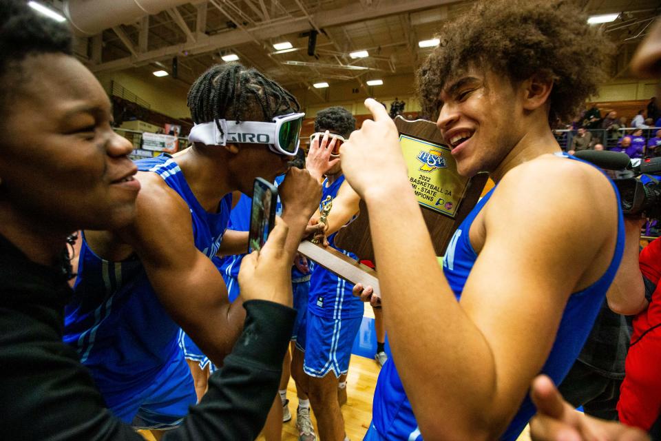 Marian's Dareon Thornton (2) and Zion Rhoades (4) celebrate with the trophy after winning the Marian vs. Leo semistate championship boys basketball game Saturday, March 19, 2022 at Northside Gym in Elkhart. 