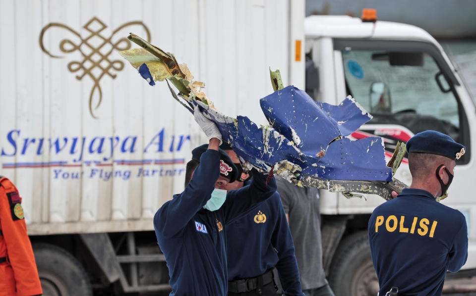 FILE - In this Jan. 11, 2021, file photo, police officers carry a part of aircraft recovered from Java Sea where a Sriwijaya Air passenger jet crashed, at Tanjung Priok Port in Jakarta, Indonesia. A malfunctioning automatic throttle may have caused the pilots of the Sriwijaya Air jet to lose control, leading to the plane's plunge into the Java Sea last month, Indonesian investigators said Wednesday., Feb. 10, 2021. (AP Photo/Dita Alangkara, File)