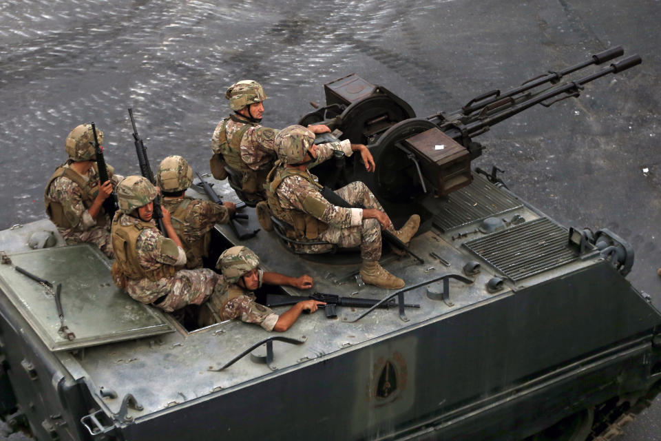 Lebanese army soldiers sit on their armored vehicles as they deployed to contain the tension after heavy fire in the coastal town of Khaldeh, south of Beirut, Lebanon, Sunday, Aug. 1, 2021. At least two people were killed on Sunday south of the Lebanese capital when gunmen opened fire at the funeral of a Hezbollah commander who was killed a day earlier, an official from the group said. (AP Photo/Bilal Hussein)