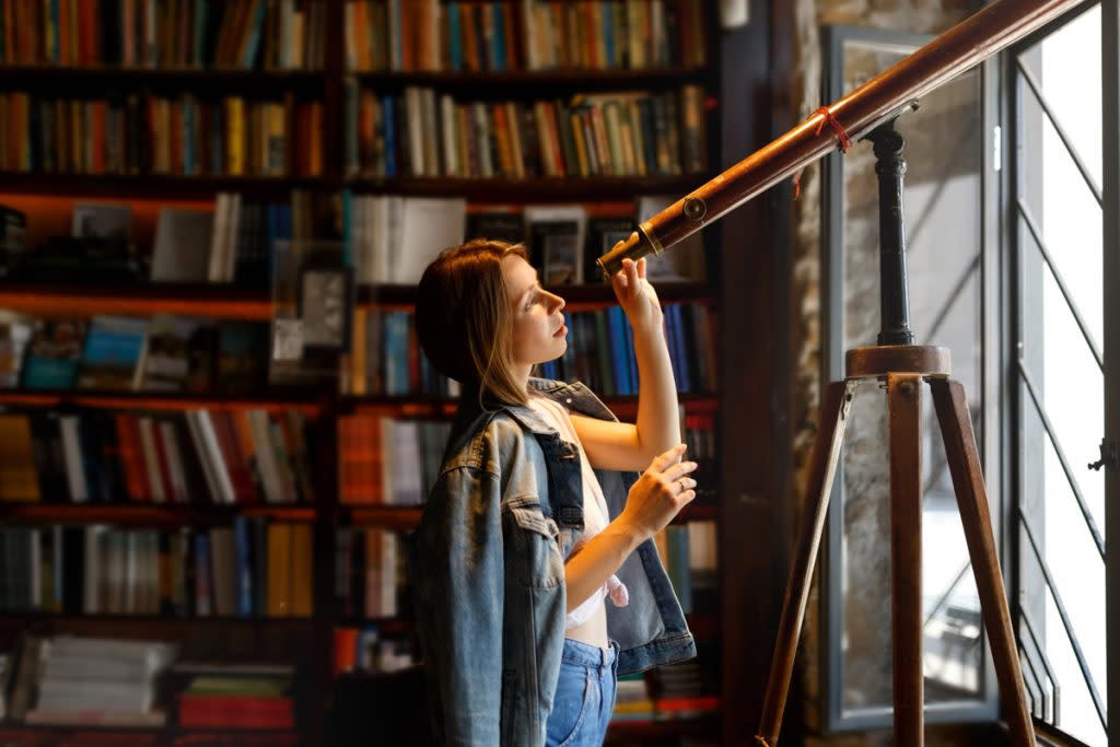 A woman looks through a microscope at a public library. 