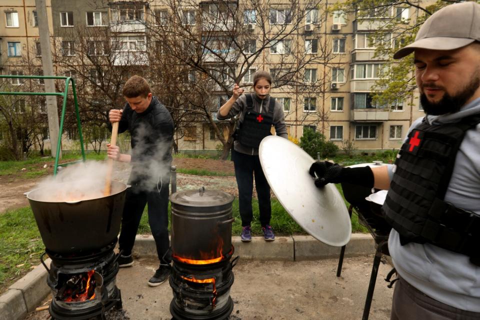 three volunteers cooking outdoors