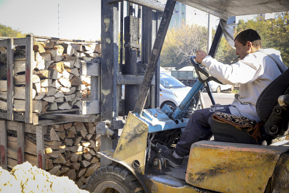 A firewood vendor moves pallets outside Chisinau, Moldova, Saturday, Oct. 15, 2022. Europe's energy crisis, triggered by Russia slashing natural gas flows amid its war against Ukraine, has forced some people to turn to cheaper heating sources like firewood as the weather gets colder. But as more people stock up and burn wood, prices have skyrocketed, shortages and thefts have been reported, and scams are emerging. (AP Photo/Aurel Obreja)